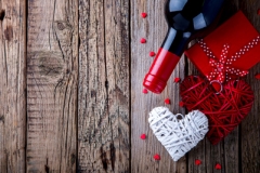 Gift ,  heart and the bottle of red wine for a romantic holiday Valentine's day on vintage wooden background.Celebration of Love and Happiness..Vintage style.selective focus.